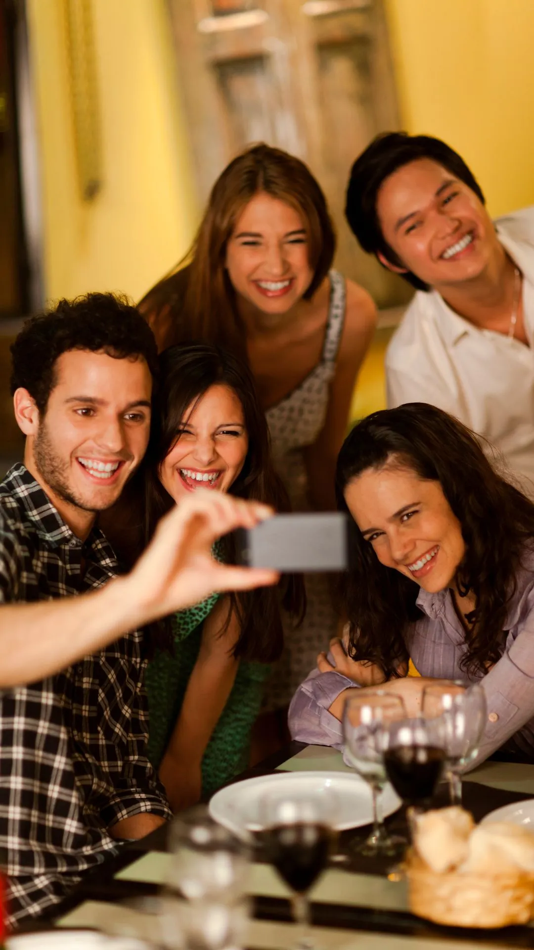 Friends taking a group selfie around a dinner table